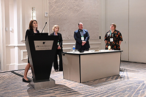 group of 4 speakers stand at the front of a room