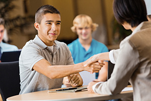 Student shaking hands with an higher education recruiter.