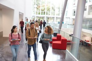 college students walk and talk with mobile devices in university building