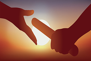 One person passing a baton to another with the sun setting in the background.