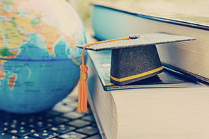 Photograph of a globe, books, and graduation cap.