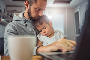 man sitting at laptop with child on lap
