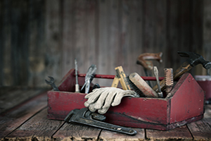 Red tool box full of tools on wooden bench.