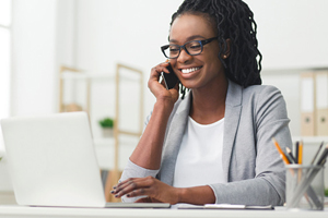 female works on laptop while smiling on the phone