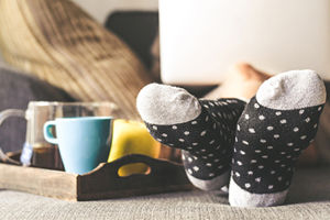 a person wearing cozy socks and working on a laptop next to a tray of tea