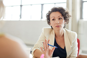 office setting: a tense-faced woman holding up her hand to her colleague