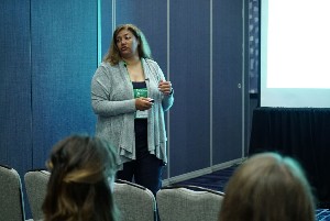 Female standing as she speaks to audience members.