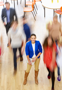 Lone female wearing a blue jacket stands still while others walk past her in a blur.