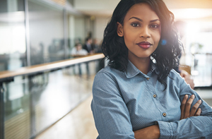 Women of color stands with her arms crossed as she looks directly at the camera.