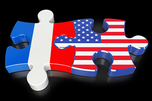 Two interlocking puzzle pieces, one with the French flag on it and the other with the U.S. flag.