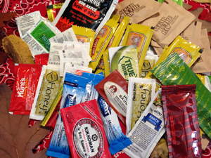 Photo of a pile of assorted sauce packets including soy sauce, ketchup, mustard, etc.