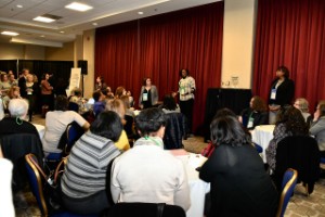 Photo taken from the audience's perspective looking at a stage of panelists.