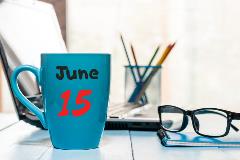 Photograph of a workspace with laptop and coffee cup with the date June 15 printed on it.