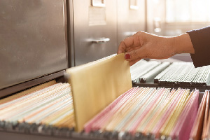 Hand picking out a manilla folder from a filing cabinet.