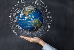 Hand holding a globe with various symbols surrounding it. 