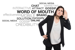 Female listening with her hand to her ear with a word cloud visible behind her with words such as; word of mouth, brand, chat, credibility, etc.