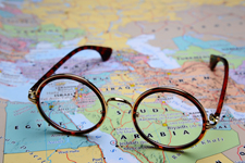 Pair of eye glasses placed on a world map focused on the middle east.