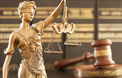 Bronze statute of blindfolded lady justice next to a wooden gavel.
