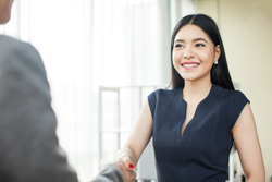 Female wearing a blue top smiles at another figure out of frame. 