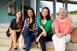 Four females sitting together on a concrete step.