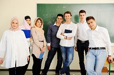 Group photo of students standing in front of a green chalkboard in a classroom.