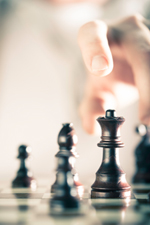 Hand reaching for a black colored Queen chess piece.