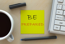 Yellow Post-It with the words "be prepared" written on it and a mug of coffee and keyboard visible next to it.