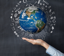 Hand holding a globe with various symbols surrounding it. 