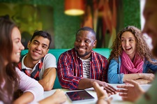 Diverse group of young adults smiling around a restaurant table. 