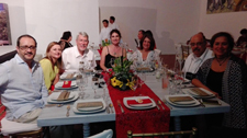 Photo of people smiling around a dinner table in what appears to be a private residence.