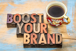 Wooden blocks with letters spelling "boost your brand" next to a mug of coffee.