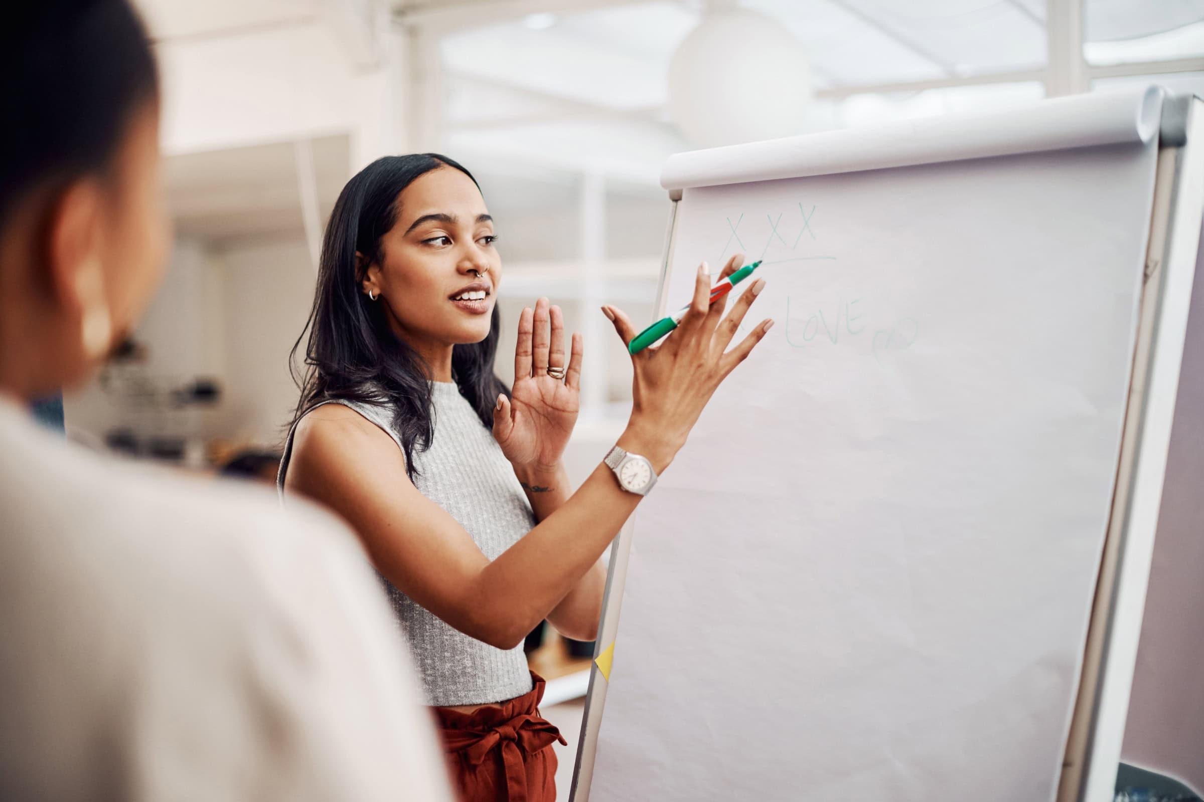 Teacher writing on a whiteboard while explaining a lesson to students in a classroom
