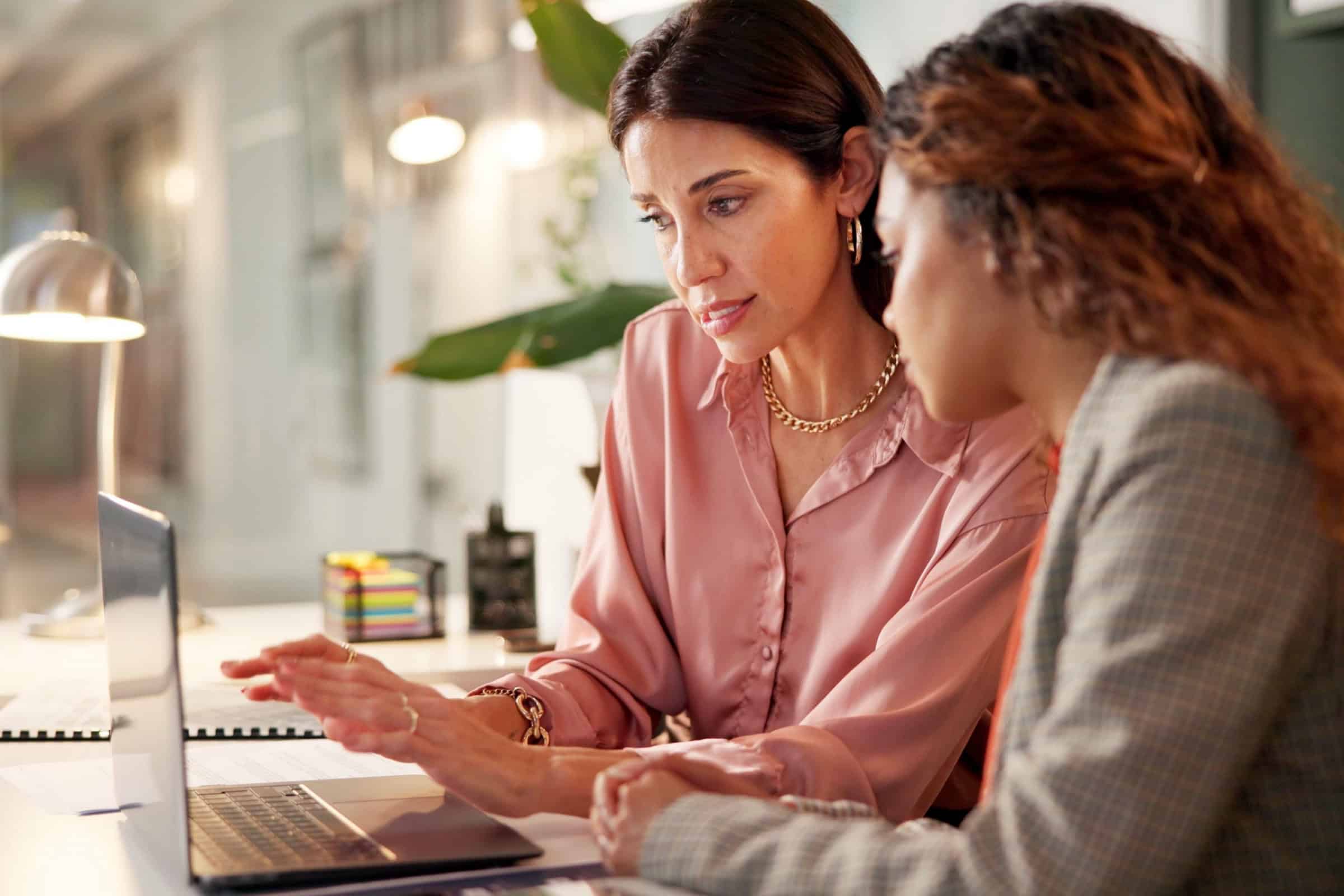 Two women discussing at a laptop during AACRAO conference.