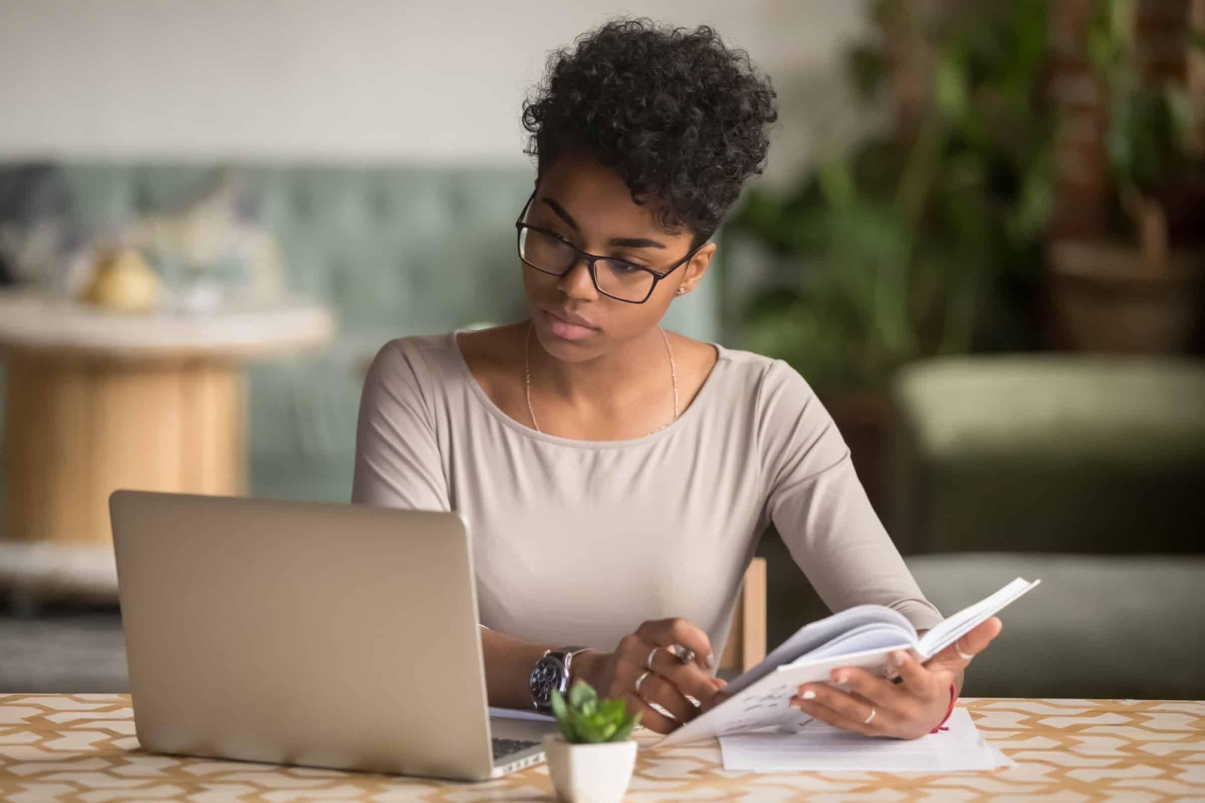 Student studying with laptop and notebook for academic planning.