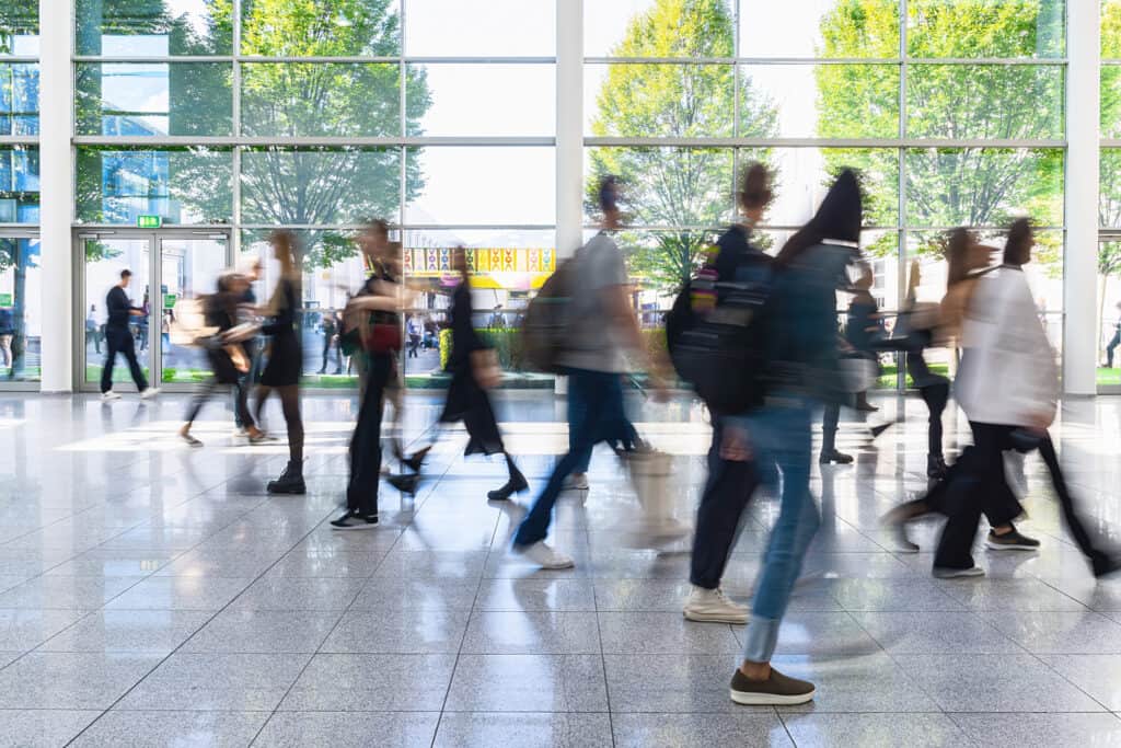 People walking through a bright office lobby, creating motion blur