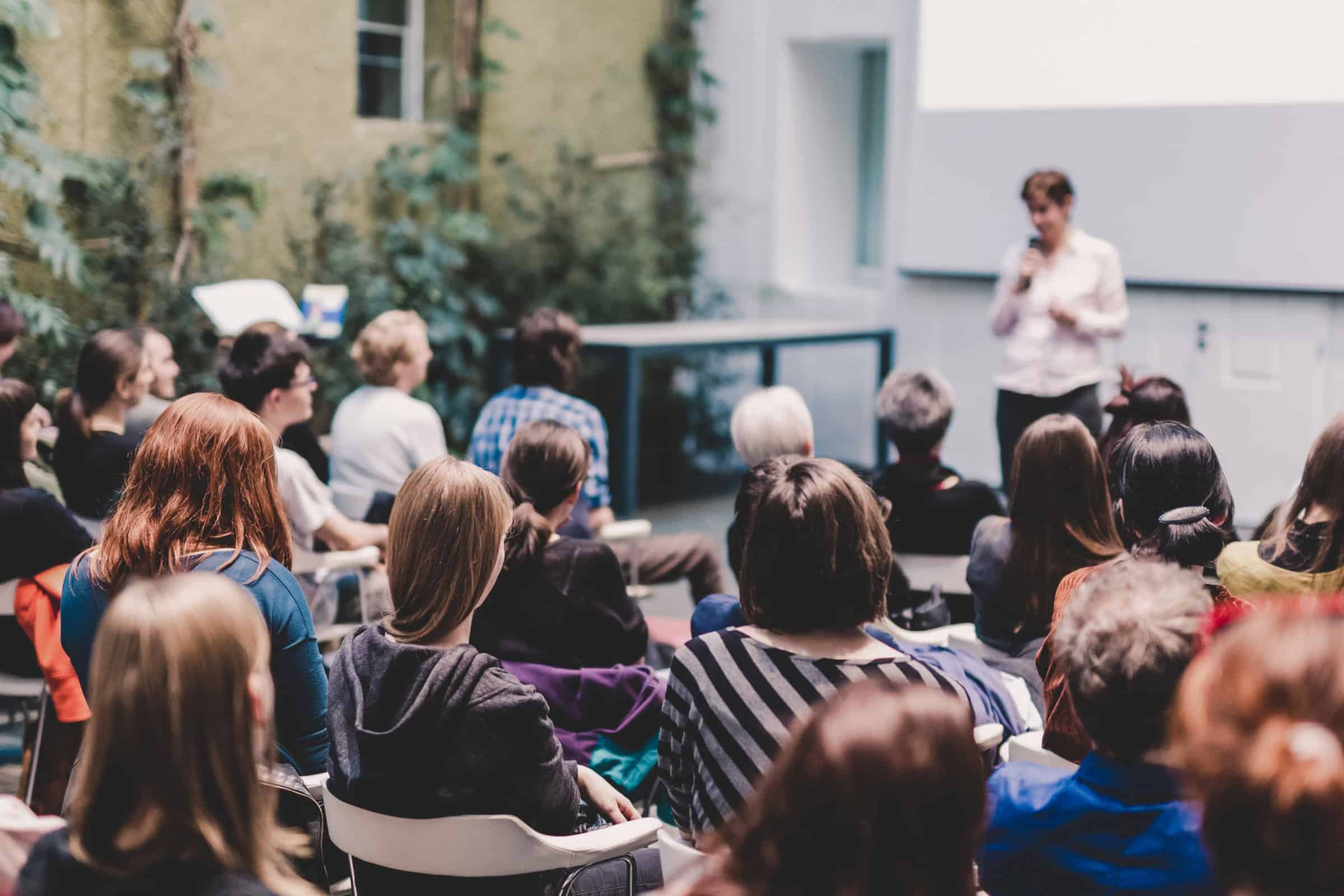 Outdoor seminar with a speaker addressing an audience seated in rows