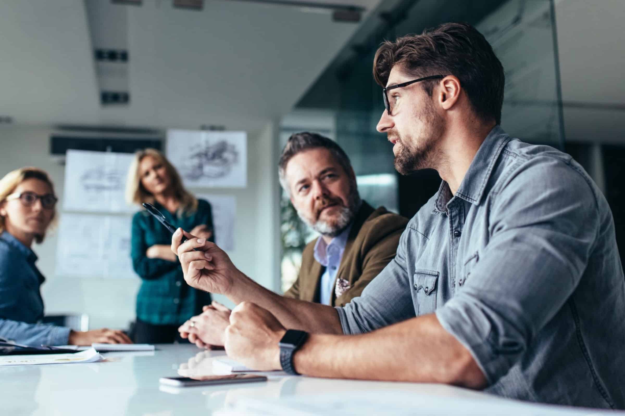 Team meeting with one man speaking while others listen in an office