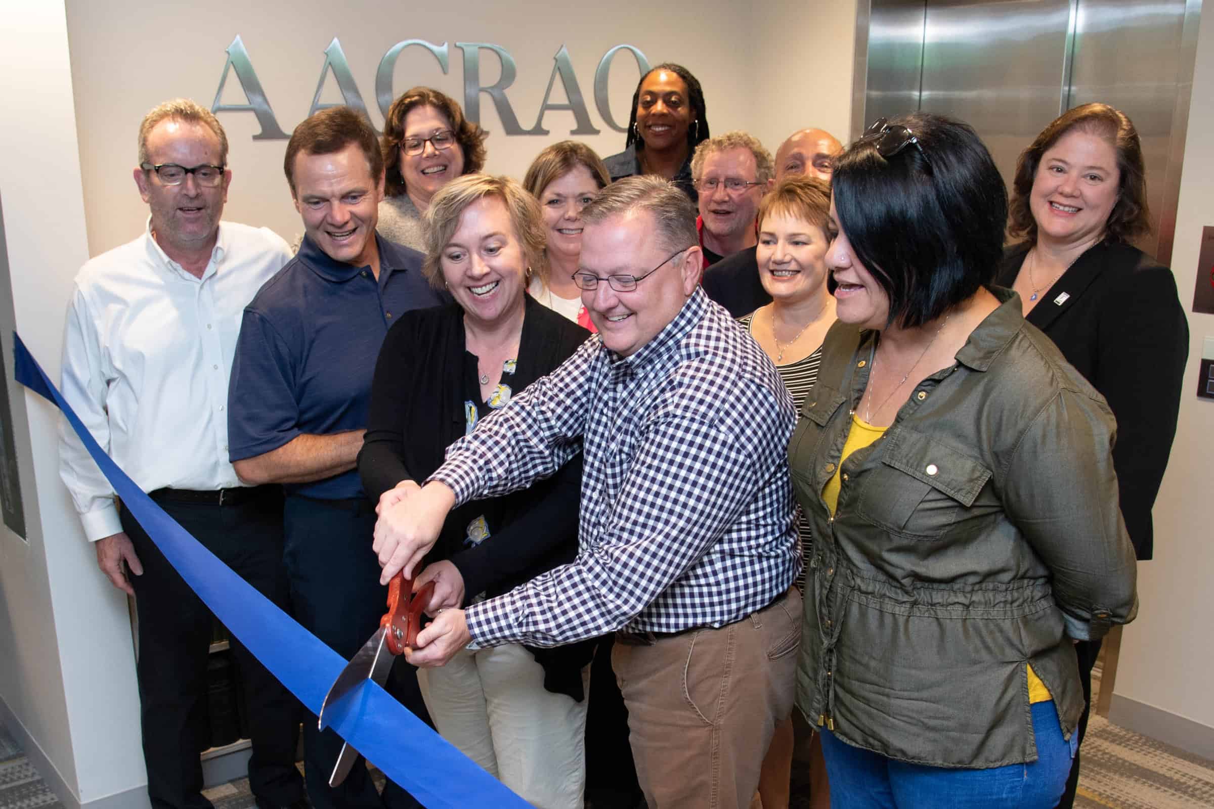 Group of people cutting a blue ribbon at an AARAO event