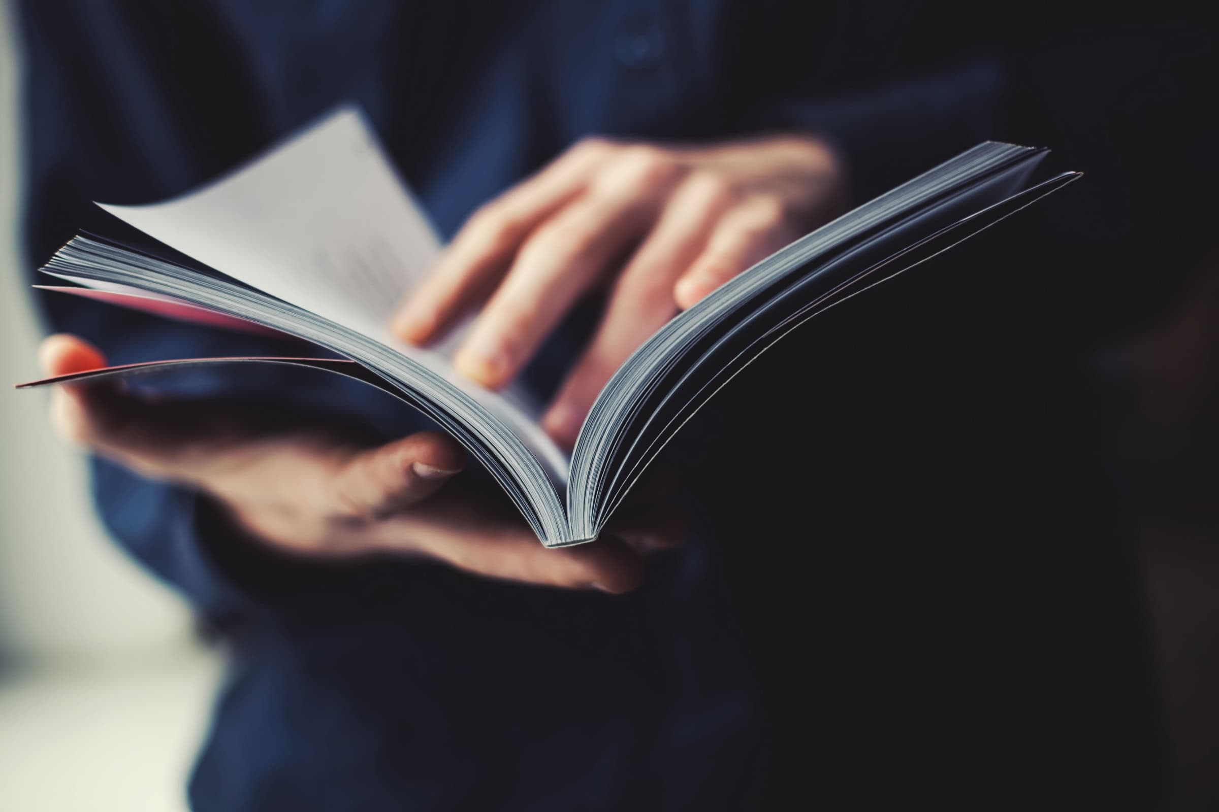 Open book with pages fanned out in a person’s hands