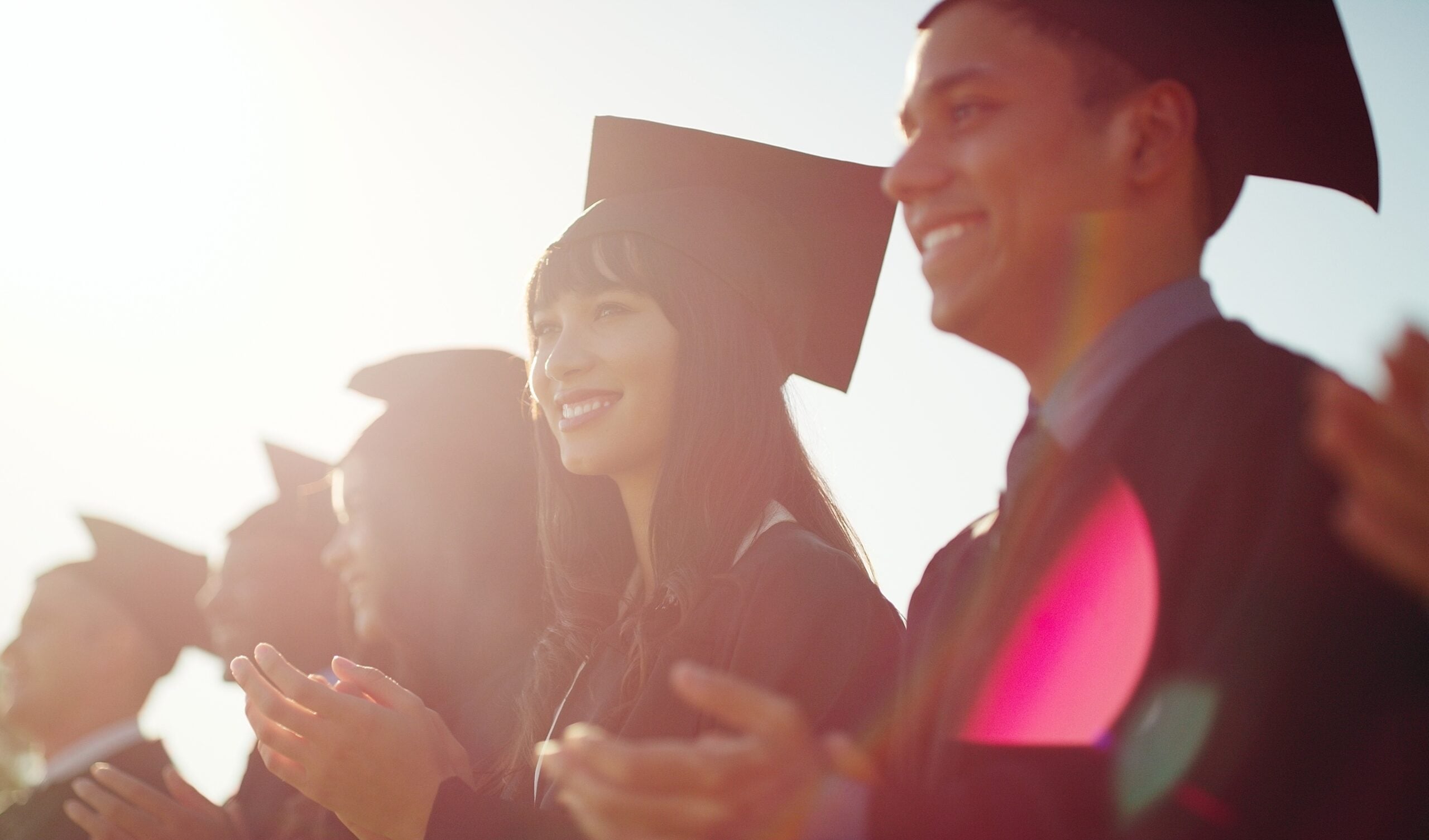 Smiling graduates in caps and gowns at a graduation ceremony.