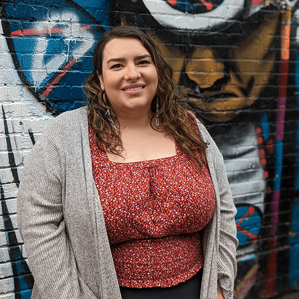 Woman smiling in front of a colorful graffiti wall