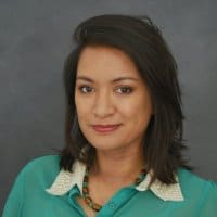 Portrait of a woman in a green blouse against a gray background