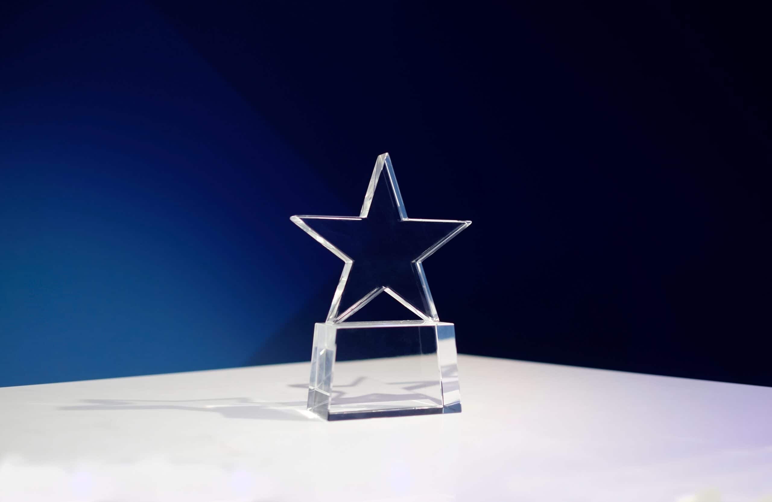 star shaped award in glass against a blue background