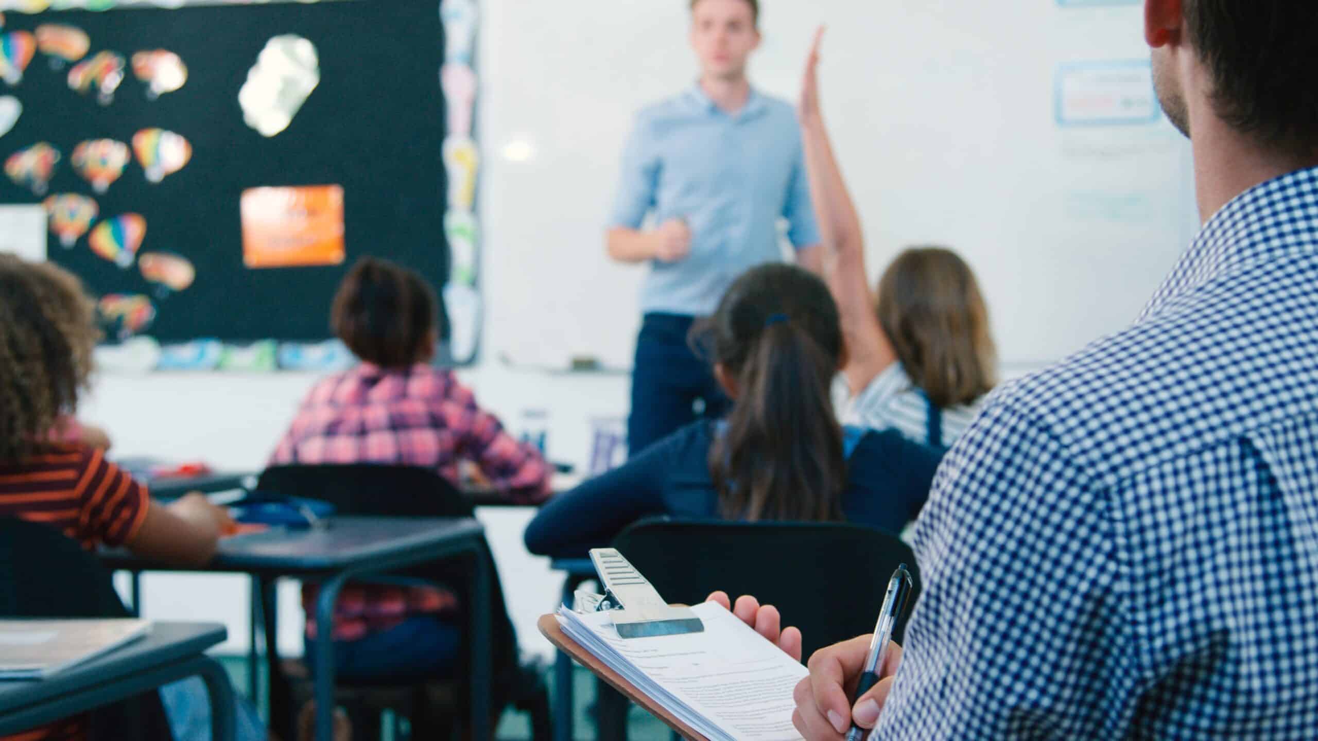 Male teacher in a classroom talking to students