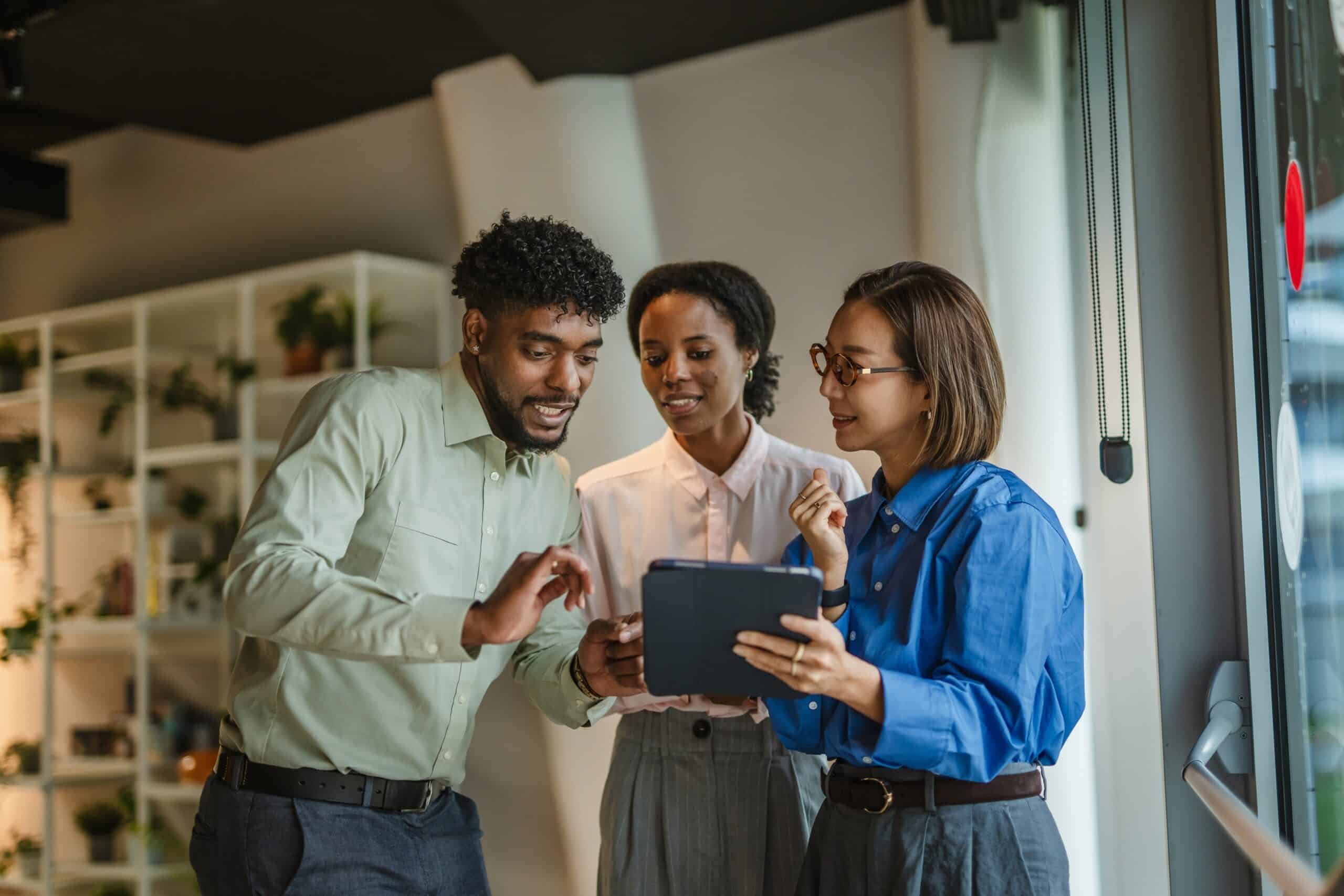Three coworkers looking at a tablet together in an office
