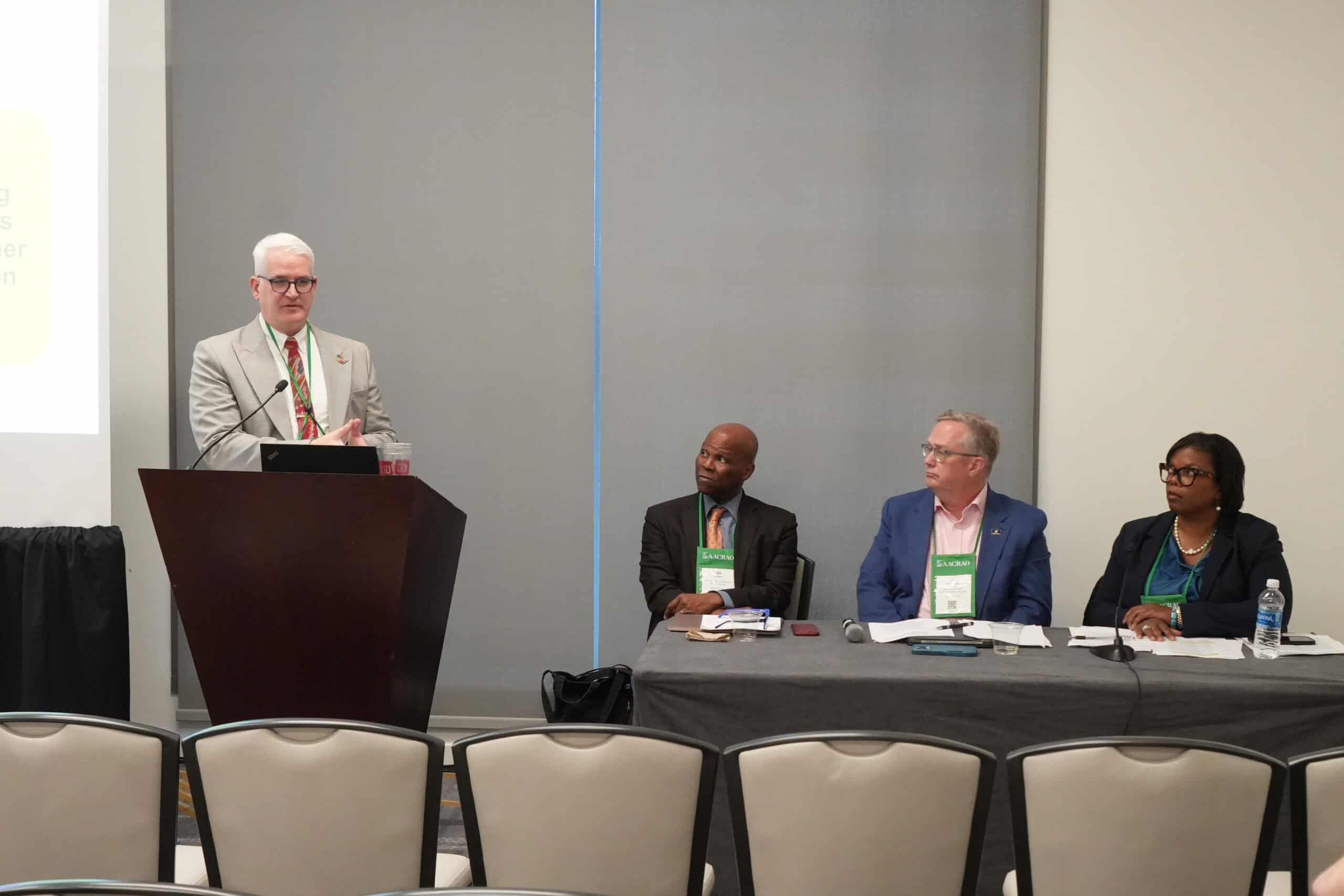 15:59Claude responded: Four panelists at an AACRAO conference session.Four panelists at an AACRAO conference session.