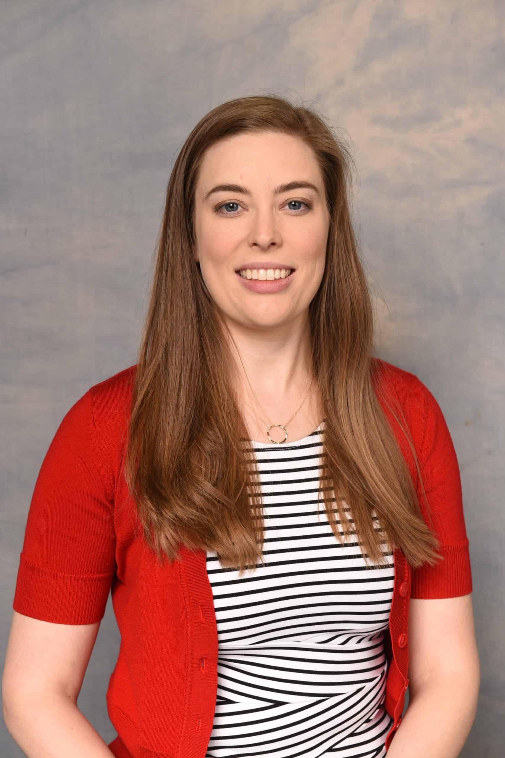 Portrait of a smiling woman wearing a red cardigan over a black-and-white striped top