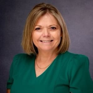 Portrait of a smiling woman in a green top against a gray background