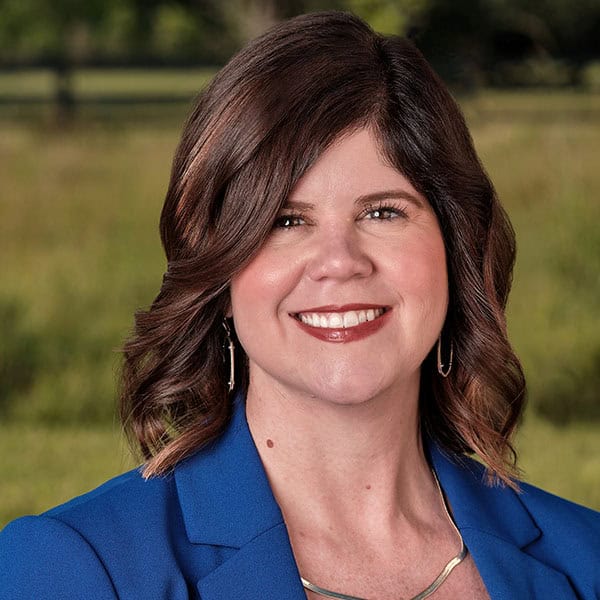 Portrait of a smiling woman in a blue blazer outdoors