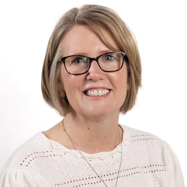 Portrait of a smiling woman wearing glasses and a white sweater